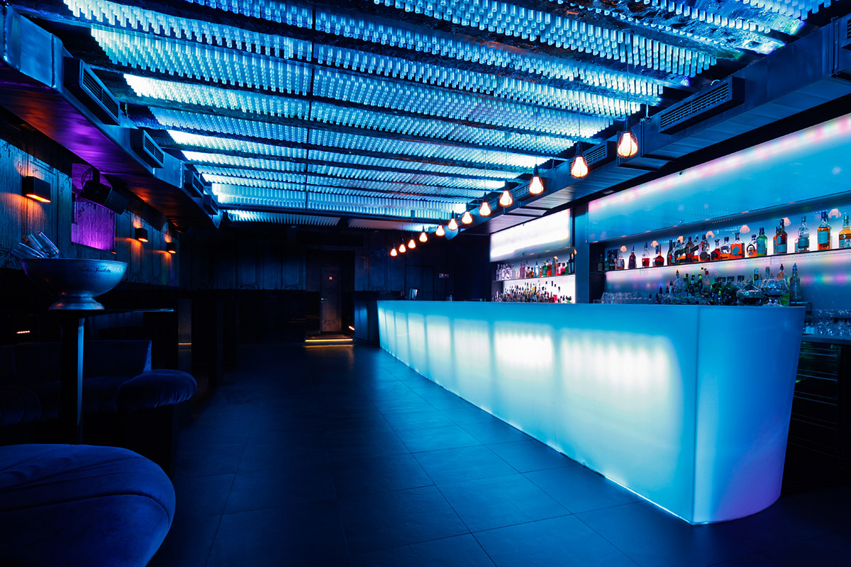 Stakleni šank u modernom interijeru bara, osvijetljen plavim svjetlom