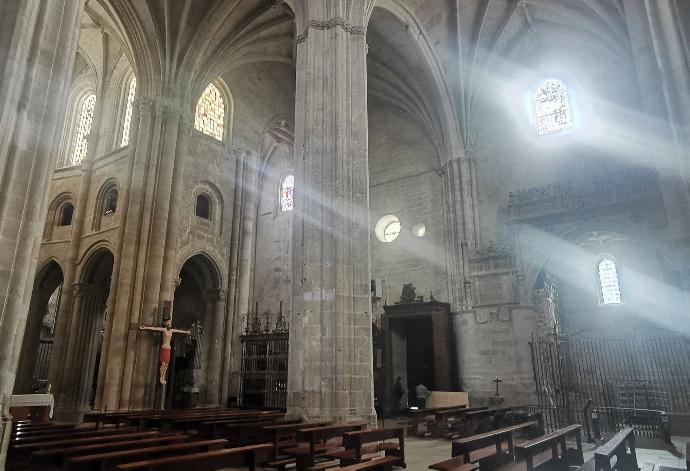 Unutrašnjost gotičke katedrale sa stupovima, šiljastim lukovima i svjetlošću koja ulazi kroz prozore