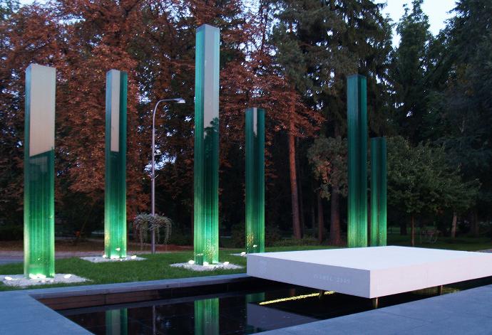 Gradski park s fontanom i šest uspravljenih staklenih monolita