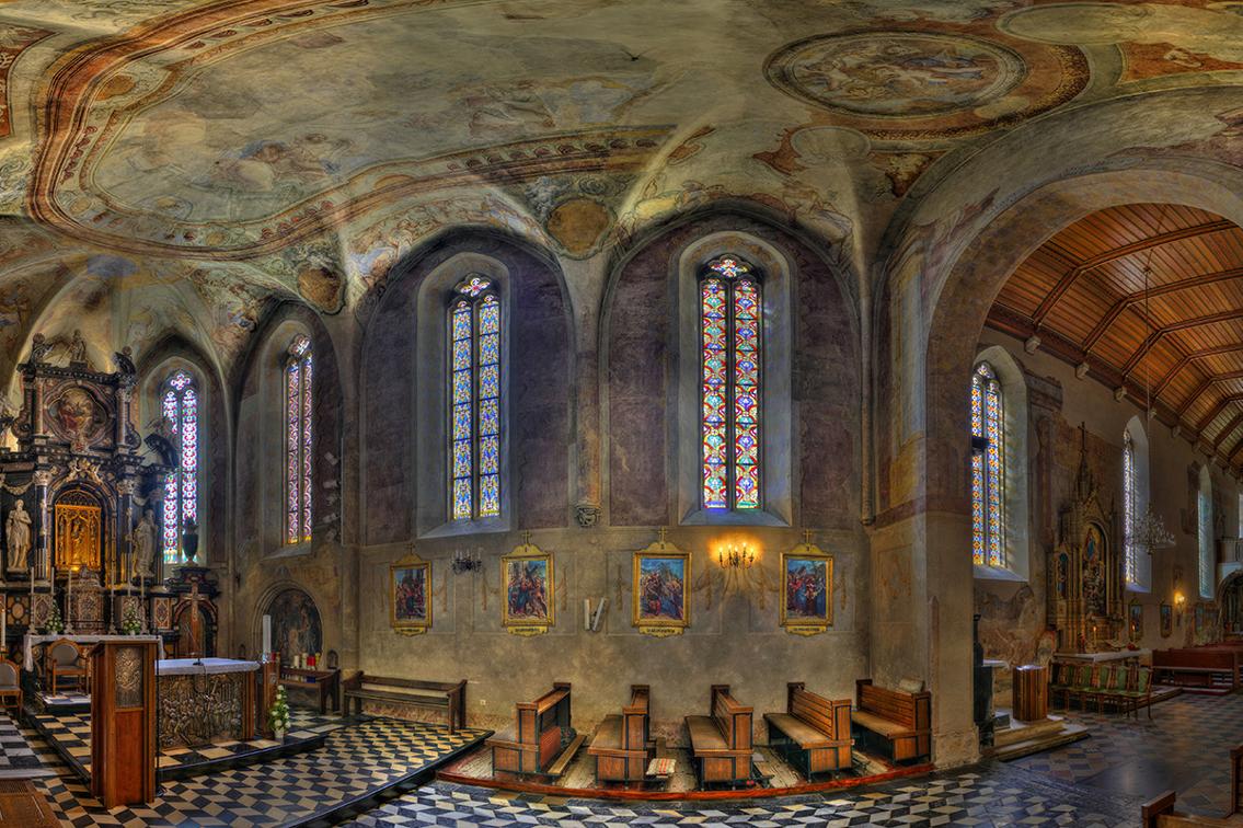 Unutrašnjost barokne crkve s vitrajima, oltarom, klupama i oslikanim stropom
