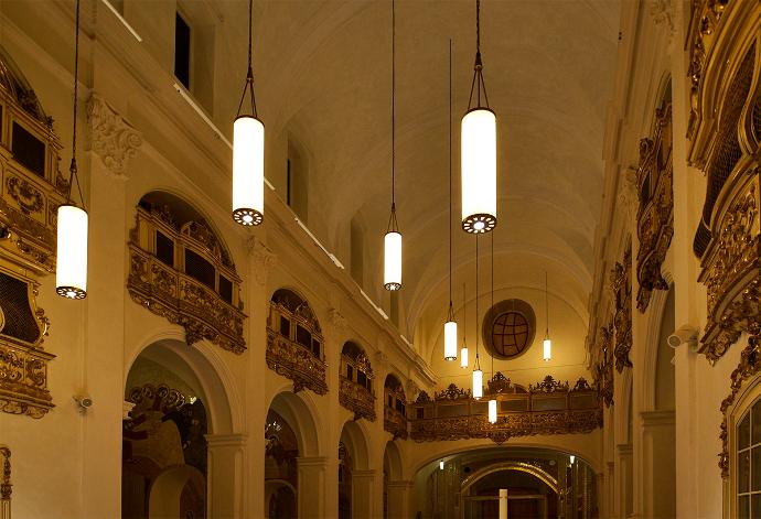 Unutrašnjost barokne crkve s polukružnim lukovima i cilindričnim svjetiljkama koje vise sa stropa
